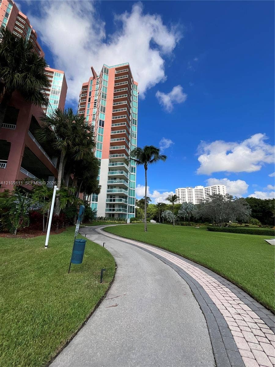 3370 Hidden Bay Drive, #801, Aventura, FL 33180 High-rise building with multiple private balconies, landscaped lawn, and paved stone walking path