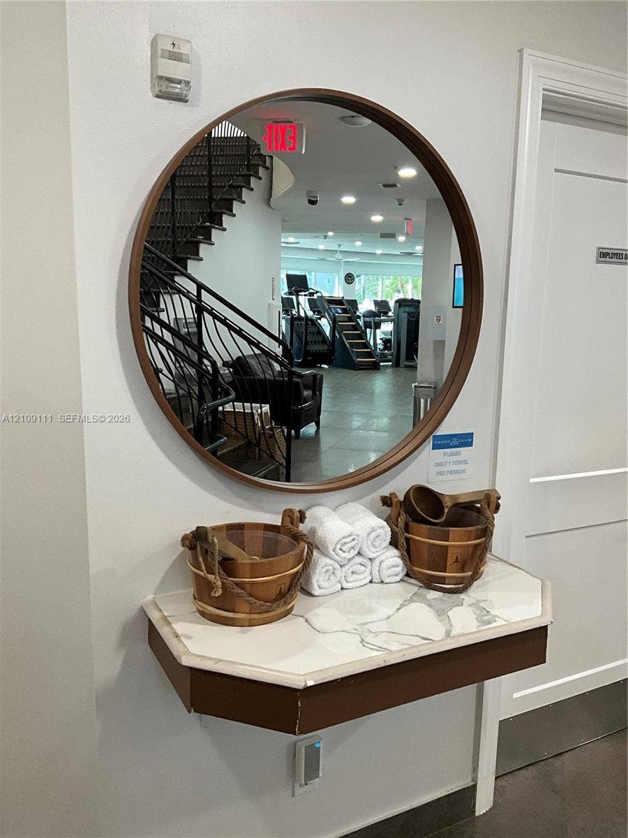 3370 Hidden Bay Drive, #801, Aventura, FL 33180 Wall-mounted floating vanity featuring a stone-look countertop and a circular mirror with a wood-finish frame