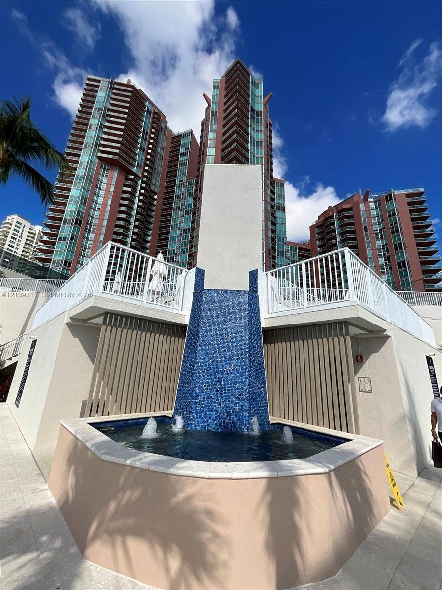 3370 Hidden Bay Drive, #801, Aventura, FL 33180 Cascading water feature with blue mosaic tiling, multi-story high-rise architecture, white metal railings, and concrete hardscaping