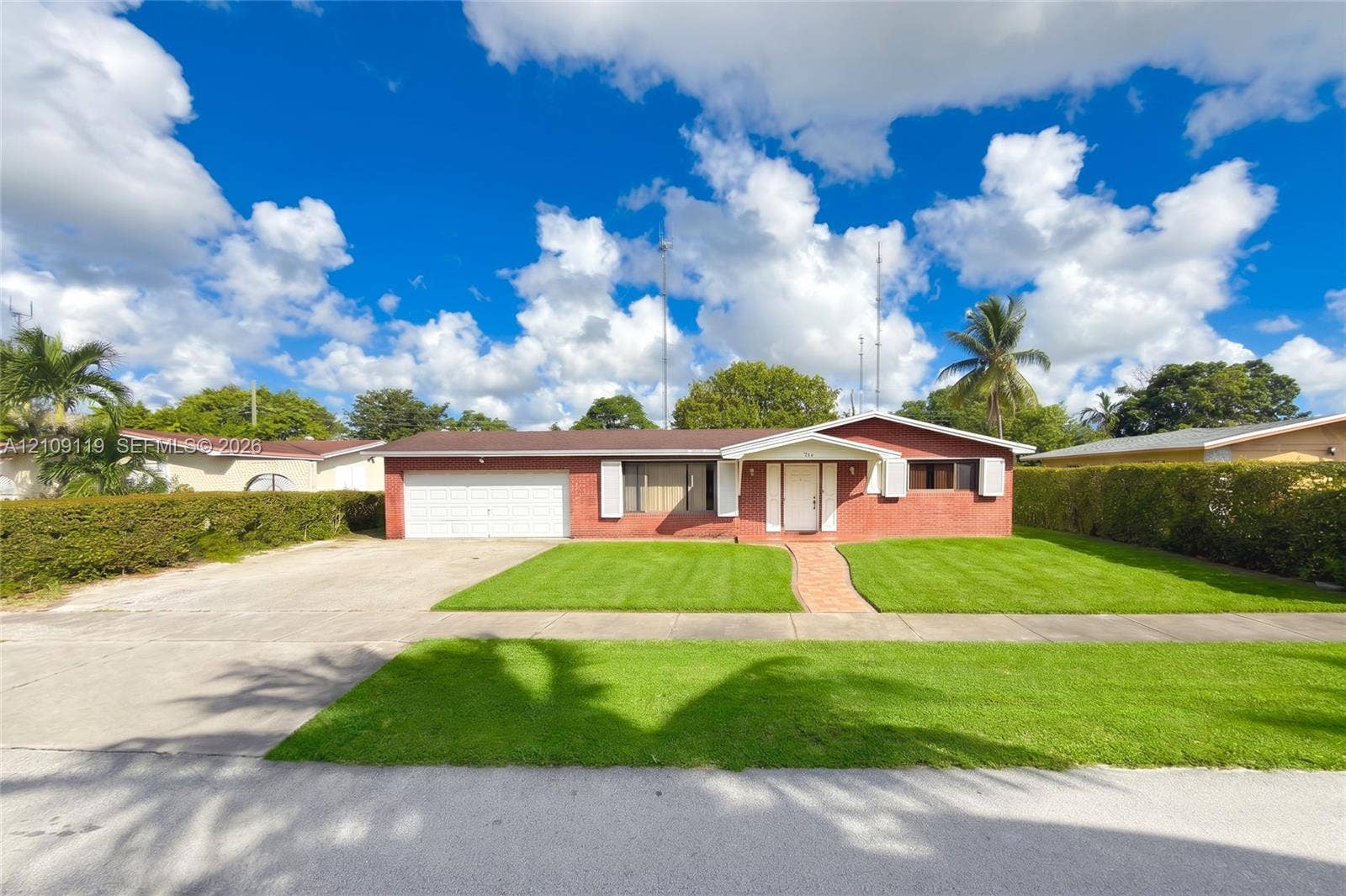 Single-story residence featuring a brick exterior, attached two-car garage, concrete driveway, and a paved walkway leading to the entrance