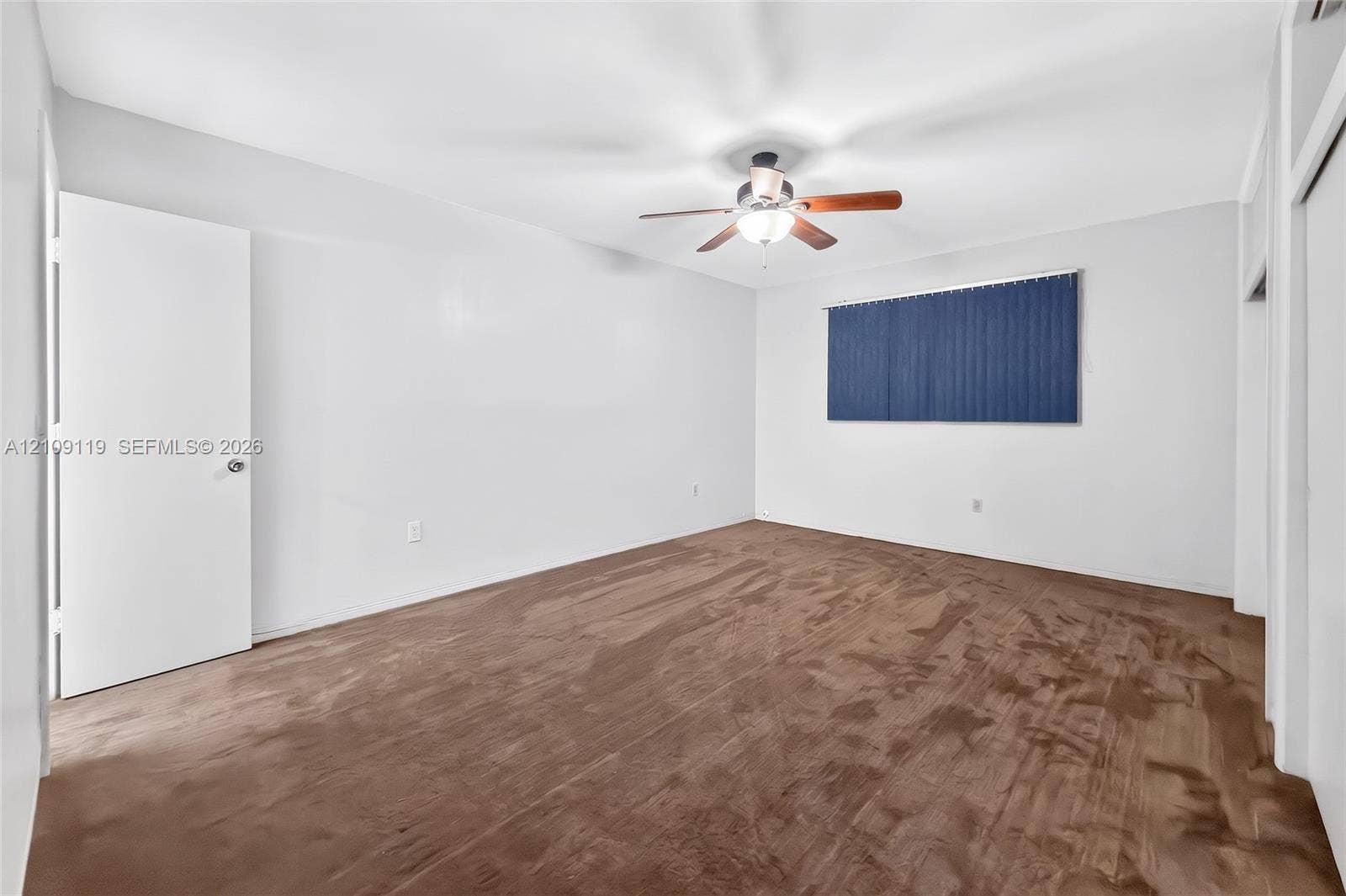 Interior room featuring neutral wall paint, wall-to-wall carpeting, a ceiling fan with integrated light fixture, and window blinds