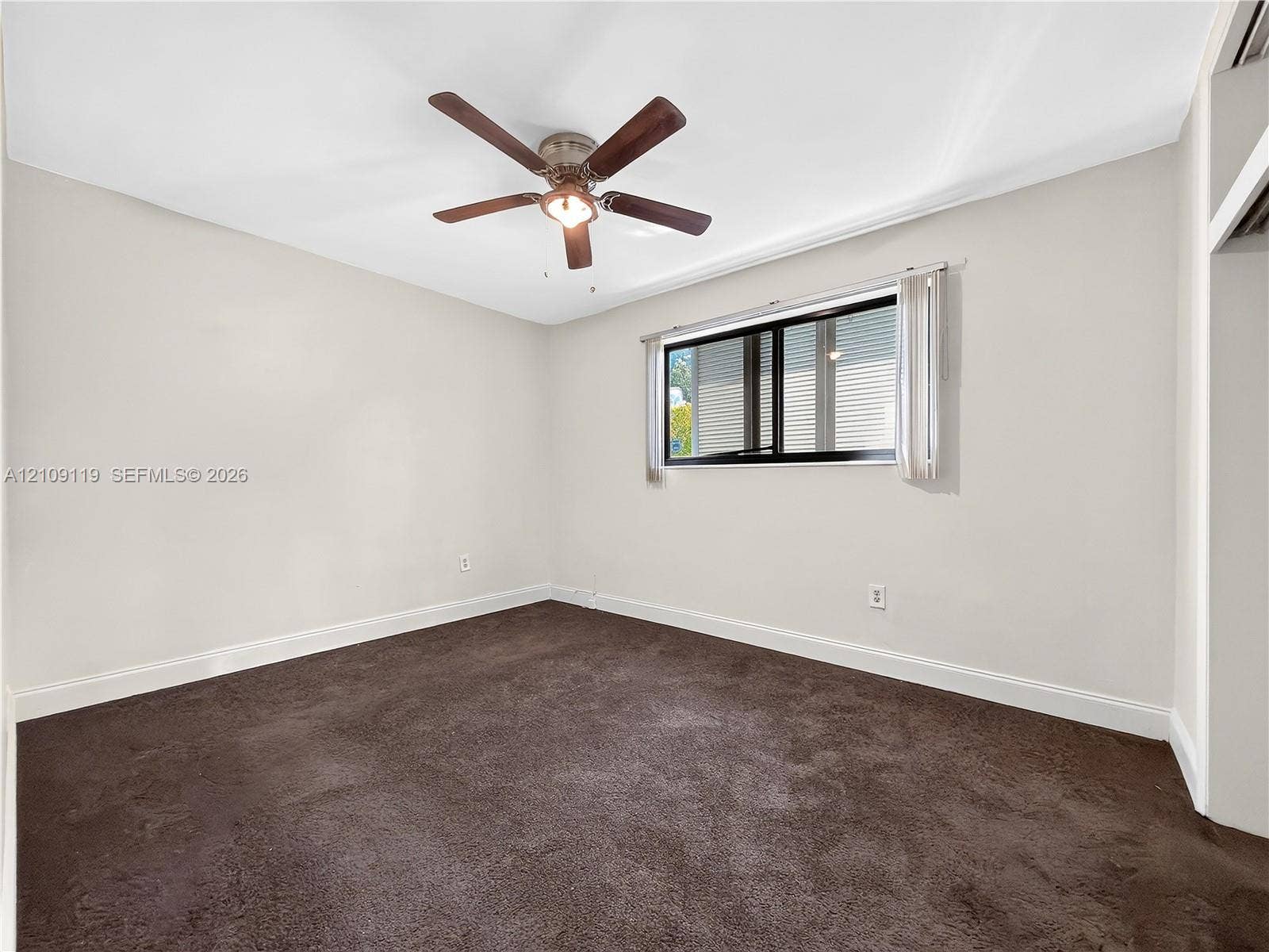 Interior space featuring neutral wall paint, wall-to-wall carpeting, a ceiling fan with integrated light fixture, and a sliding window