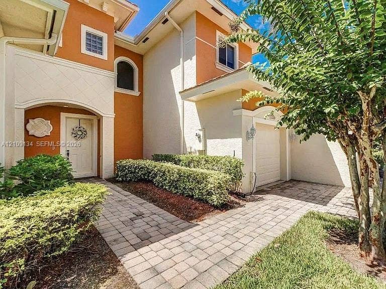2529 SW Stockbridge Square SW, Vero Beach, FL 32962 Stucco exterior featuring dual-tone facade, arched entryway, multi-paned windows, paver walkway, and attached one-car garage