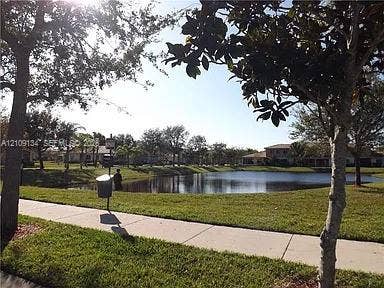 2529 SW Stockbridge Square SW, Vero Beach, FL 32962 Waterfront grounds featuring a concrete sidewalk, expansive lawn, mature trees, and a pond