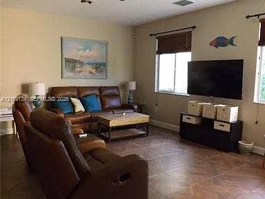 2529 SW Stockbridge Square SW, Vero Beach, FL 32962 Living area featuring large-format ceramic tile flooring, neutral wall paint, and multiple windows with installed hardware