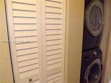 2529 SW Stockbridge Square SW, Vero Beach, FL 32962 Laundry area featuring white bi-fold louvered doors and a stacked front-load washer and dryer unit