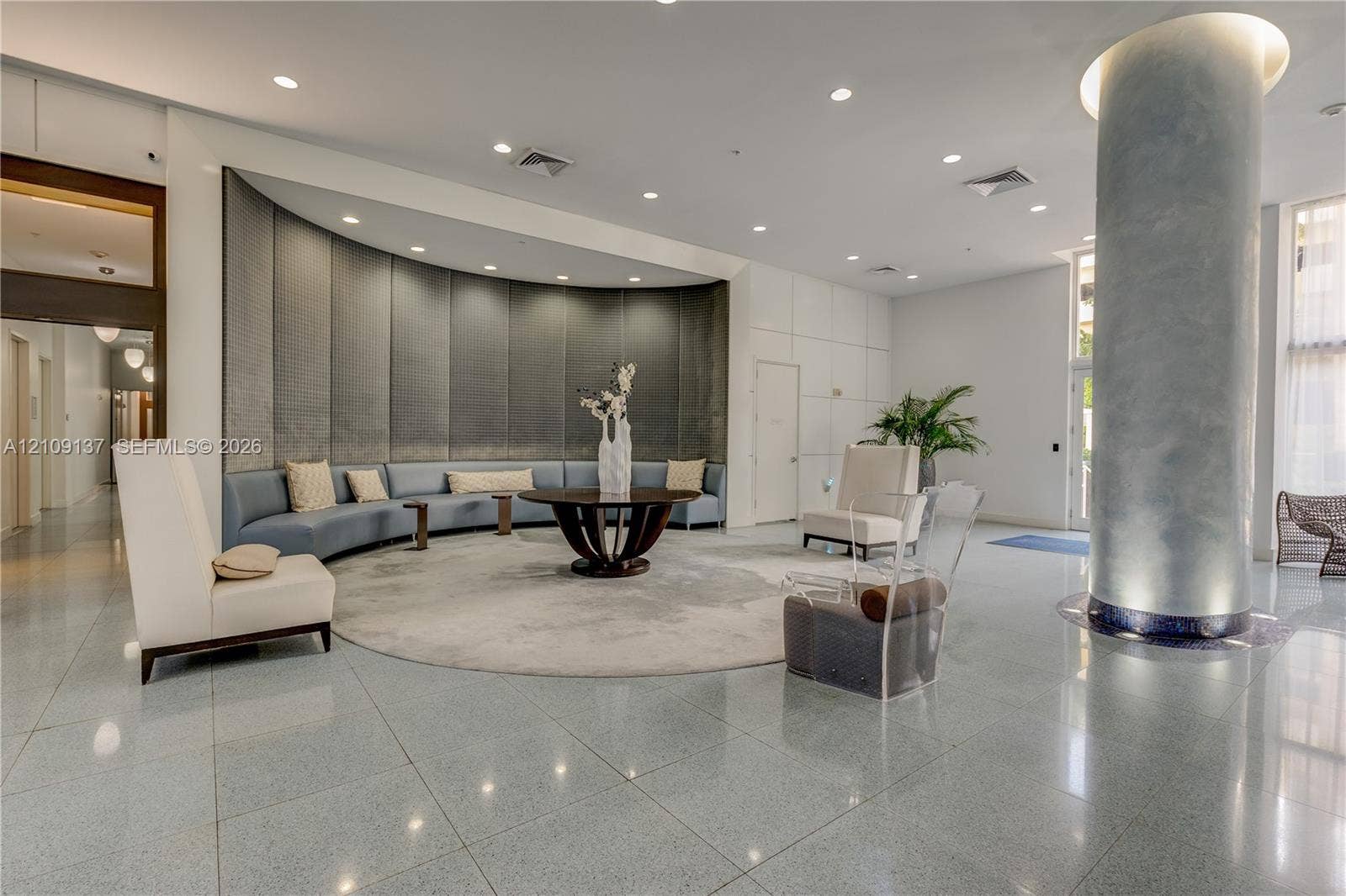 18800 NE 29th Avenue, #411, Aventura, FL 33180 Lobby featuring polished stone flooring, a prominent structural column with metallic-finish cladding, recessed lighting, and a curved, paneled feature wall