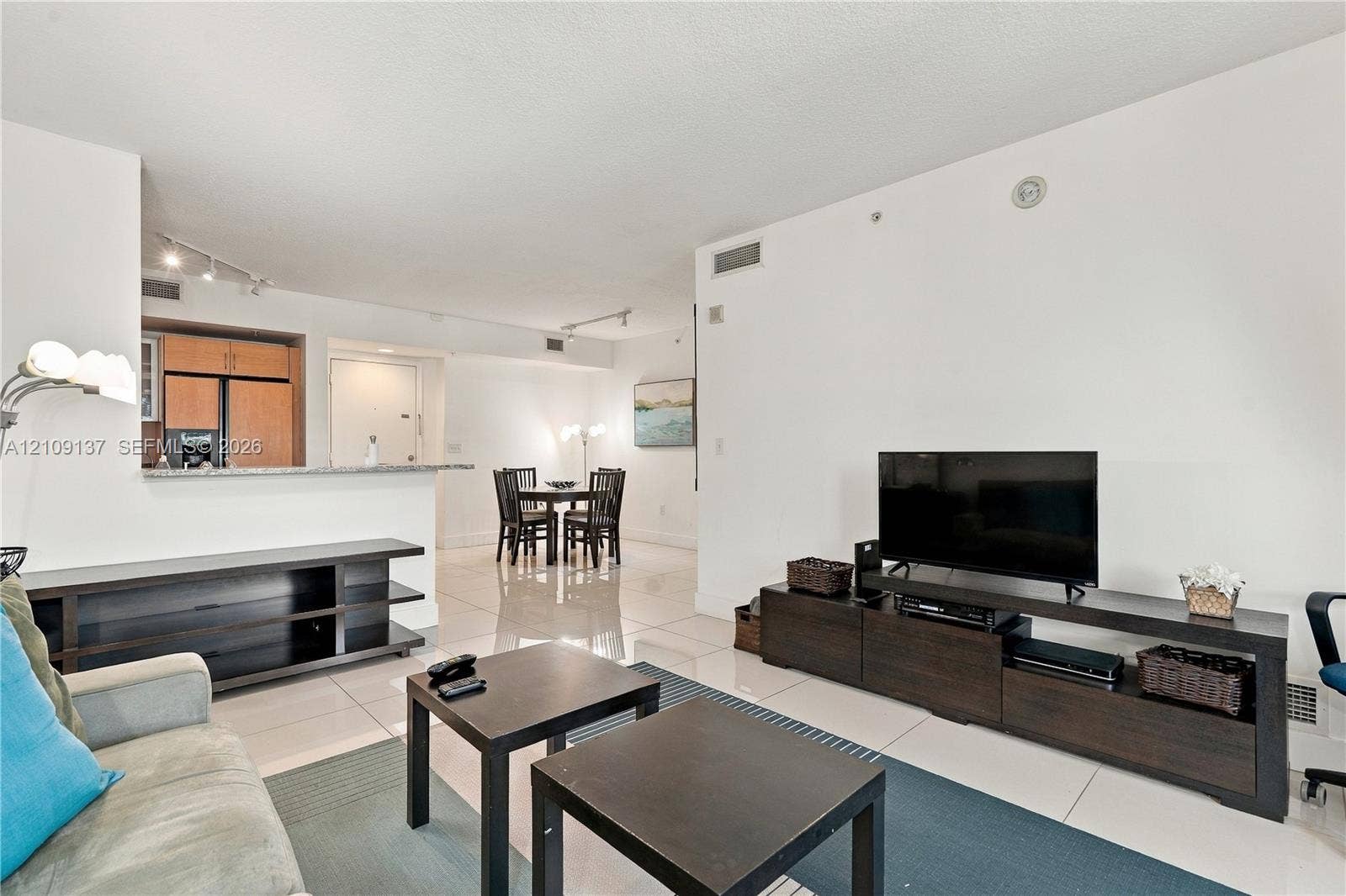 18800 NE 29th Avenue, #411, Aventura, FL 33180 Open-concept interior featuring light-toned tile flooring, recessed track lighting, and a kitchen pass-through counter with stone-finish surfacing