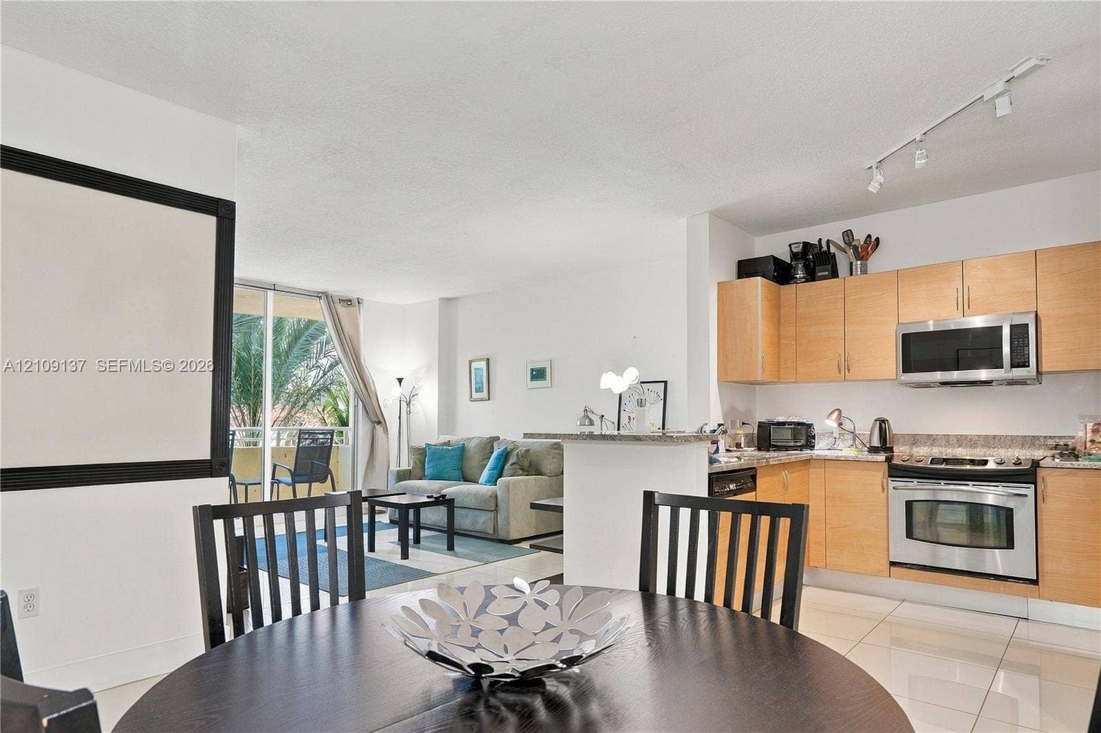 18800 NE 29th Avenue, #411, Aventura, FL 33180 Kitchen featuring light-finish cabinetry, stone-surface countertops, and stainless steel appliances, including an over-the-range microwave and electric range
