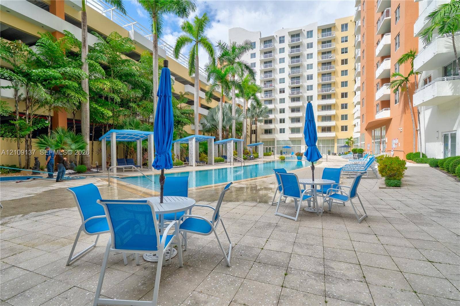 18800 NE 29th Avenue, #411, Aventura, FL 33180 Outdoor recreation area featuring a swimming pool, tiled sundeck, multiple cabanas, and mature palm trees