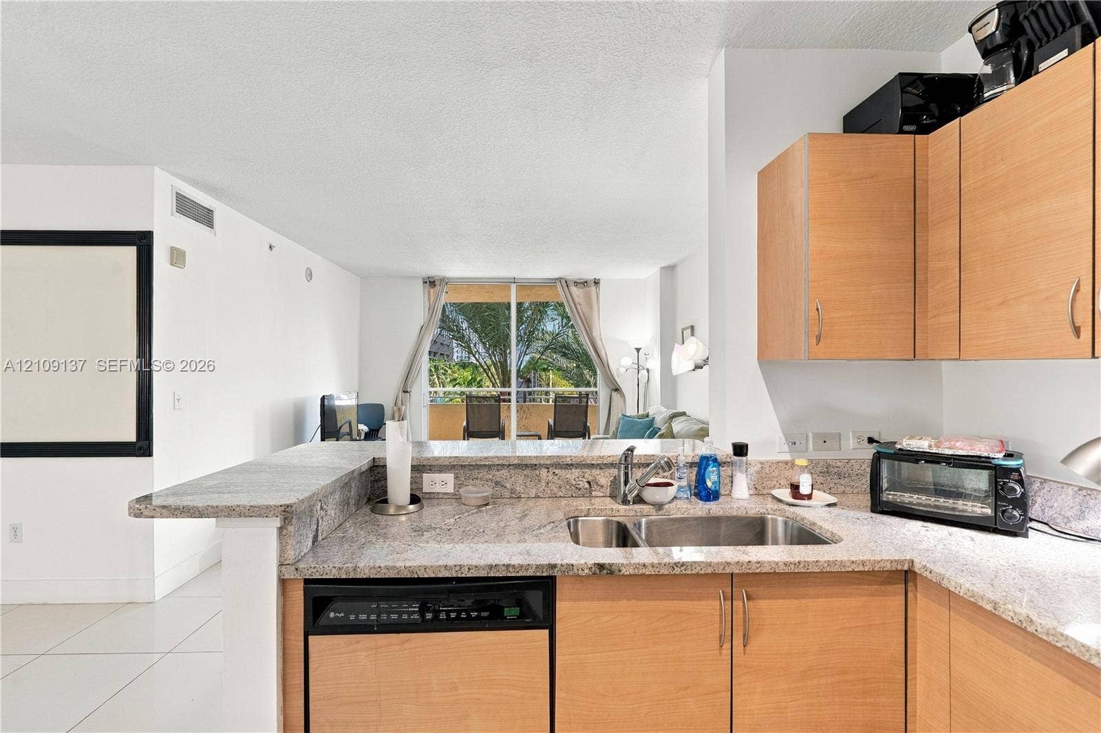 18800 NE 29th Avenue, #411, Aventura, FL 33180 Kitchen featuring natural stone countertops, light wood-finish cabinetry, stainless steel double-basin undermount sink, and integrated dishwasher