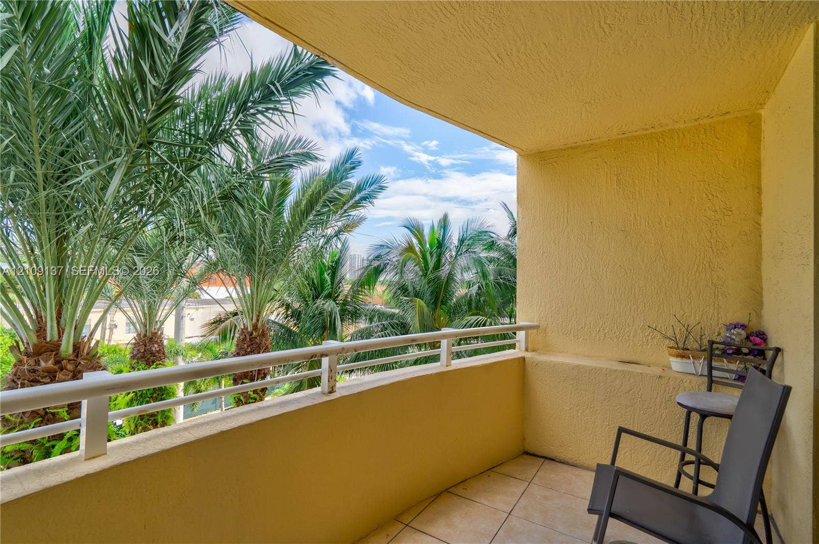18800 NE 29th Avenue, #411, Aventura, FL 33180 Covered balcony with textured stucco walls, tiled flooring, and a metal railing