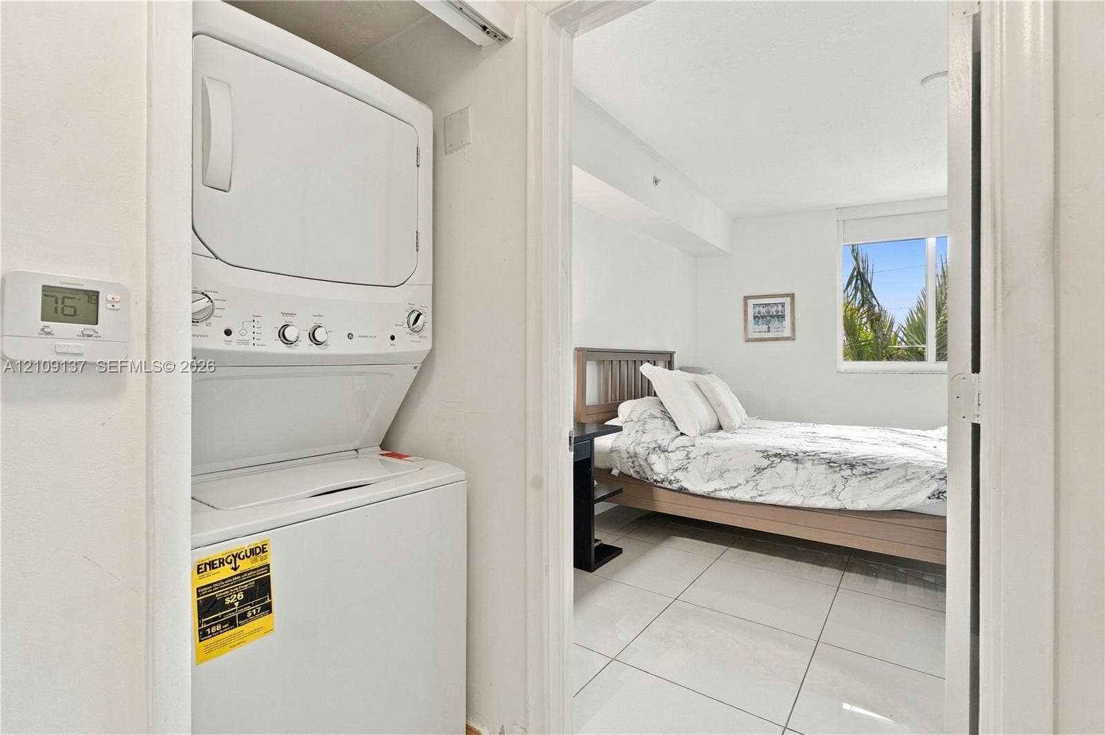 18800 NE 29th Avenue, #411, Aventura, FL 33180 Stackable laundry unit with white finish, large-format tile flooring, and window with exterior foliage