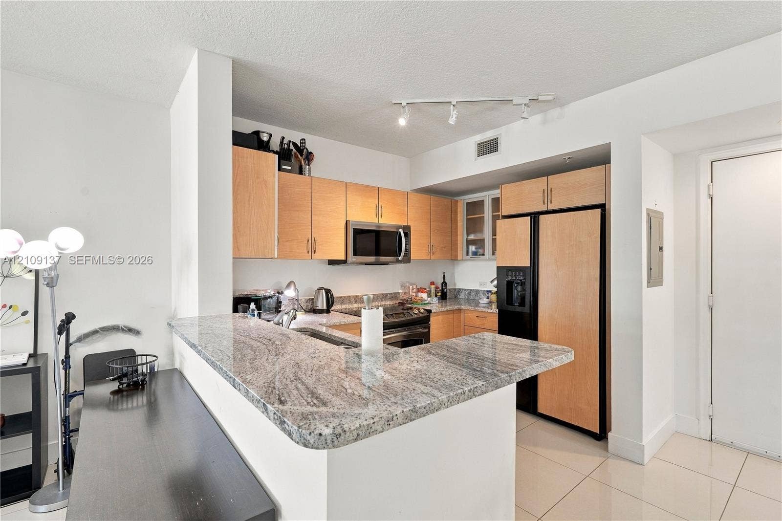 18800 NE 29th Avenue, #411, Aventura, FL 33180 Kitchen featuring light-finish cabinetry, stone countertops, a breakfast bar, stainless steel microwave, and tile flooring