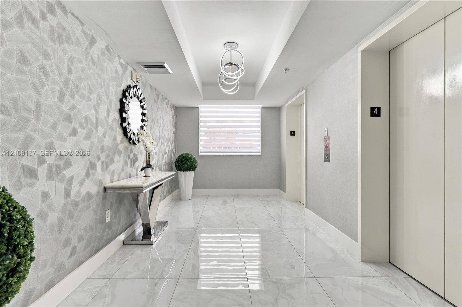 18800 NE 29th Avenue, #411, Aventura, FL 33180 Entryway featuring large-format polished tile flooring, geometric textured wall covering, recessed ceiling detail, and contemporary ring chandelier