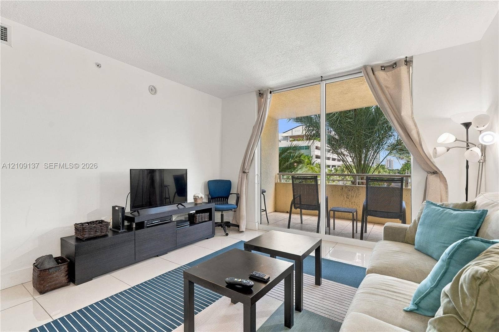 18800 NE 29th Avenue, #411, Aventura, FL 33180 Living area featuring large-format tile flooring and floor-to-ceiling glass sliding doors providing access to a private balcony