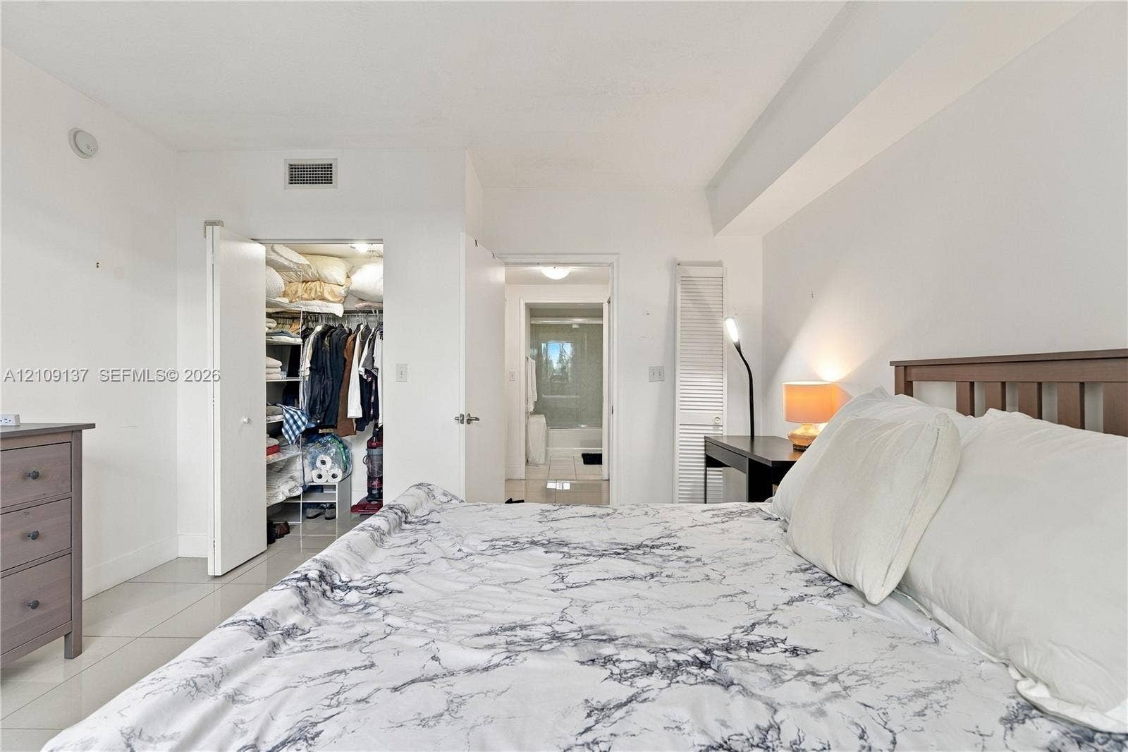 18800 NE 29th Avenue, #411, Aventura, FL 33180 Neutral-toned room with tile flooring, featuring a walk-in closet with built-in shelving, louvered closet doors, and smooth ceiling finish