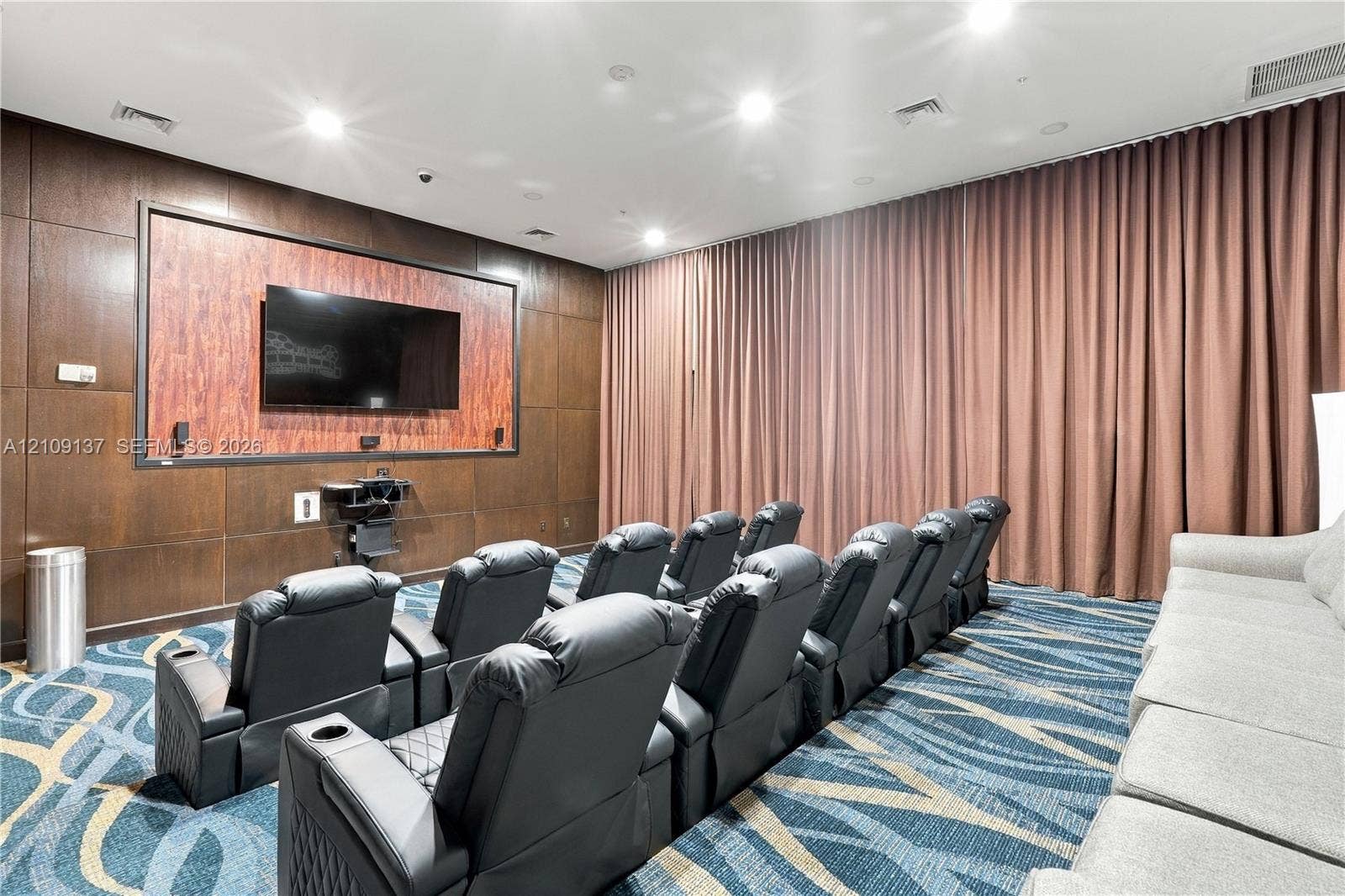 18800 NE 29th Avenue, #411, Aventura, FL 33180 Media room featuring wood-paneled walls, full-height wall drapery, and integrated recessed lighting