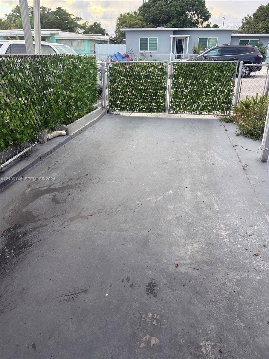 Concrete driveway featuring a gated entry with privacy screening