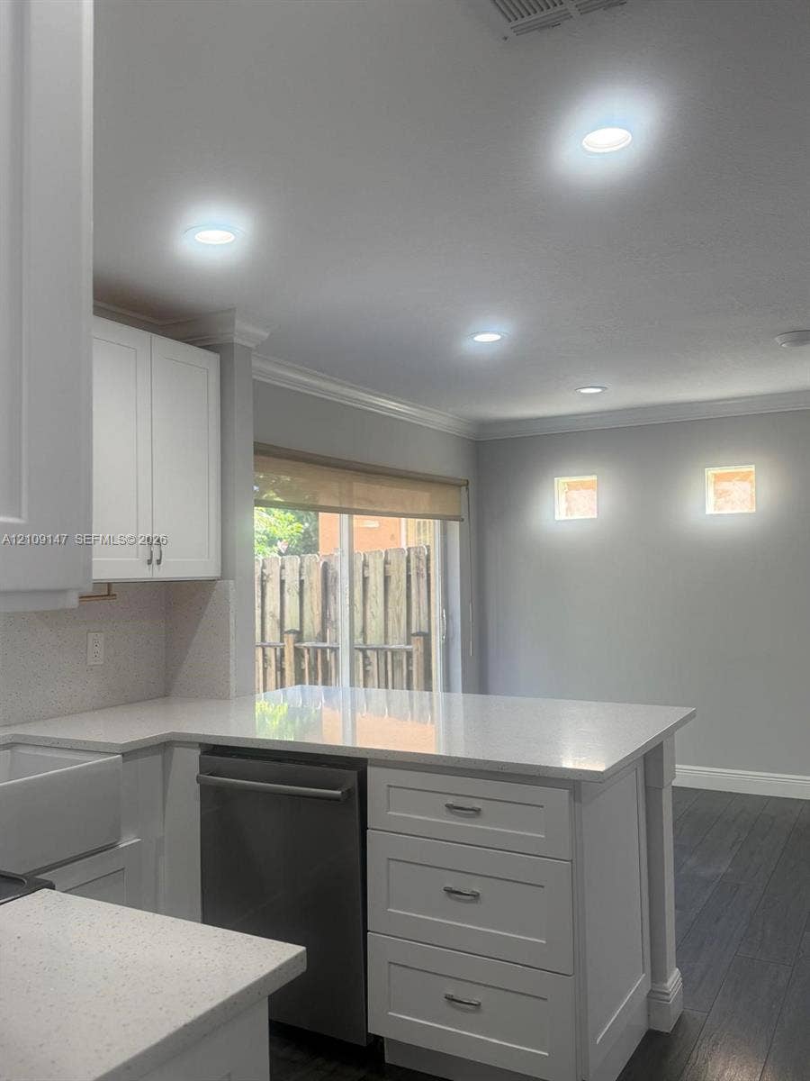 Kitchen featuring white shaker-style cabinetry, quartz countertops, stainless steel dishwasher, recessed lighting, and wood-finish flooring