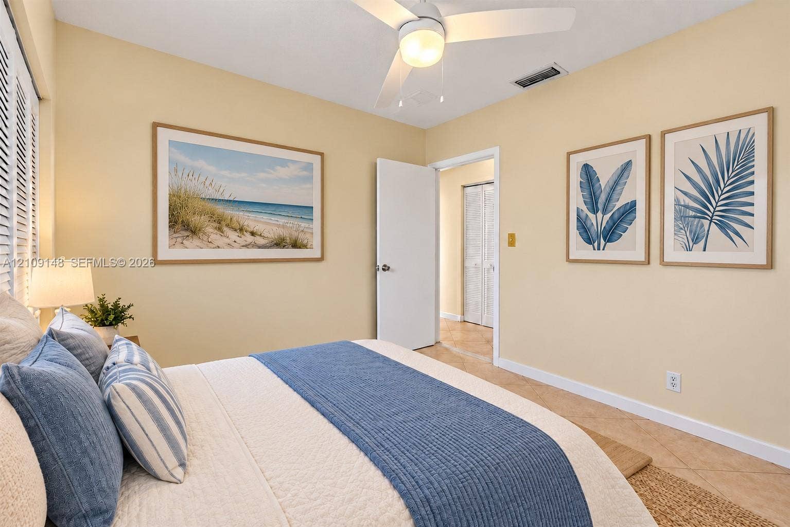 1701 SW 23rd Avenue, Fort Lauderdale, FL 33312 Neutral-toned interior space featuring light-colored tile flooring, a white ceiling fan with integrated lighting, plantation-style window shutters, and a closet with white louvered bi-fold doors