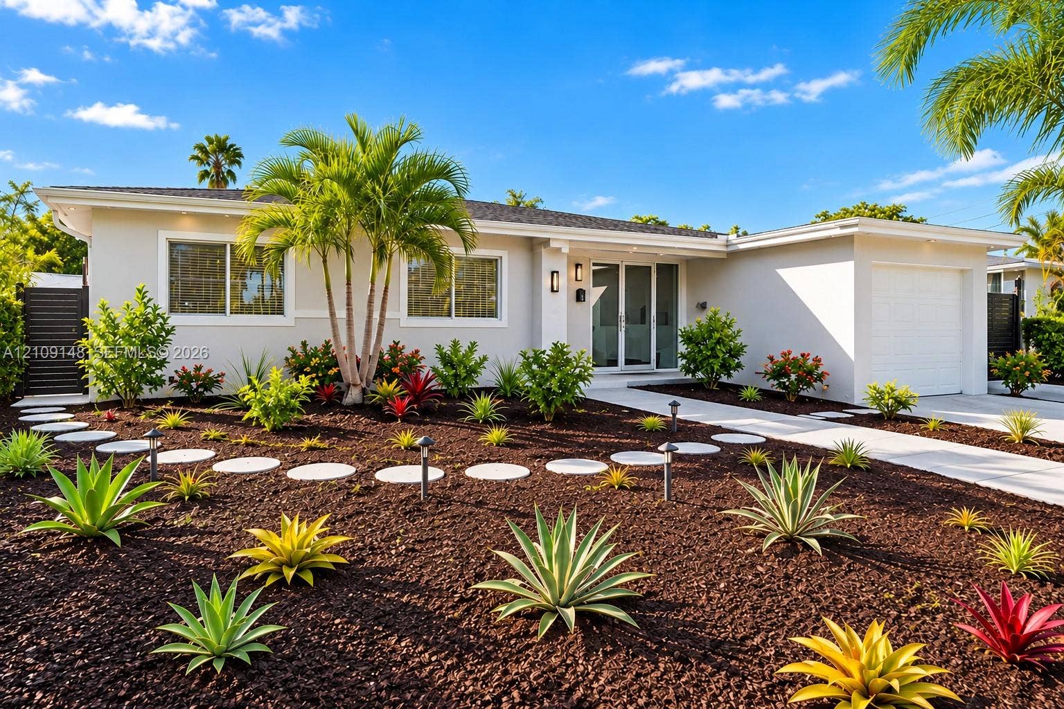 1701 SW 23rd Avenue, Fort Lauderdale, FL 33312 Single-story exterior featuring light-toned smooth stucco, a concrete paver walkway, professional xeric landscaping, mature palm trees, and an attached garage