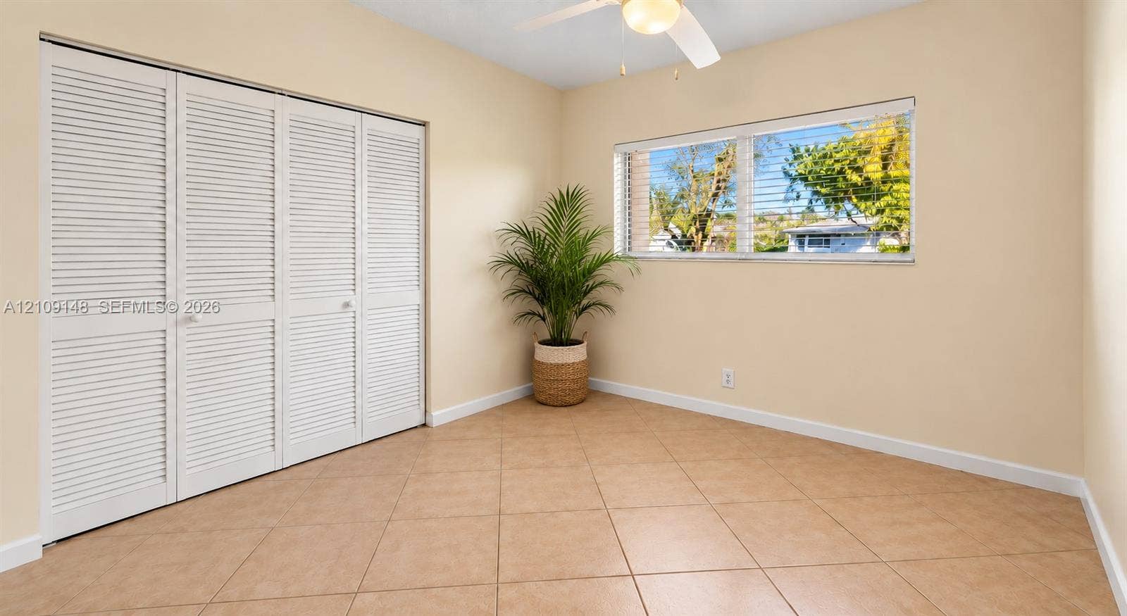 1701 SW 23rd Avenue, Fort Lauderdale, FL 33312 Room featuring neutral-toned tile flooring, louvered bi-fold closet doors, horizontal windows, and a ceiling-mounted light fixture
