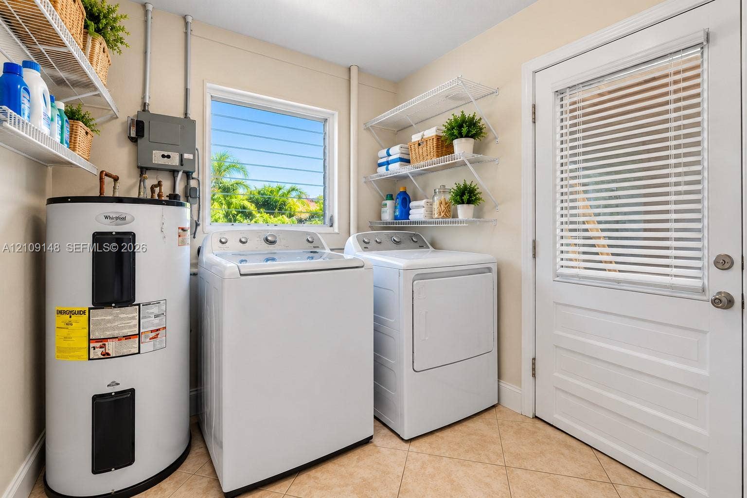 1701 SW 23rd Avenue, Fort Lauderdale, FL 33312 Laundry area featuring tile flooring, metal wall-mounted shelving, and a glass-paneled exterior door