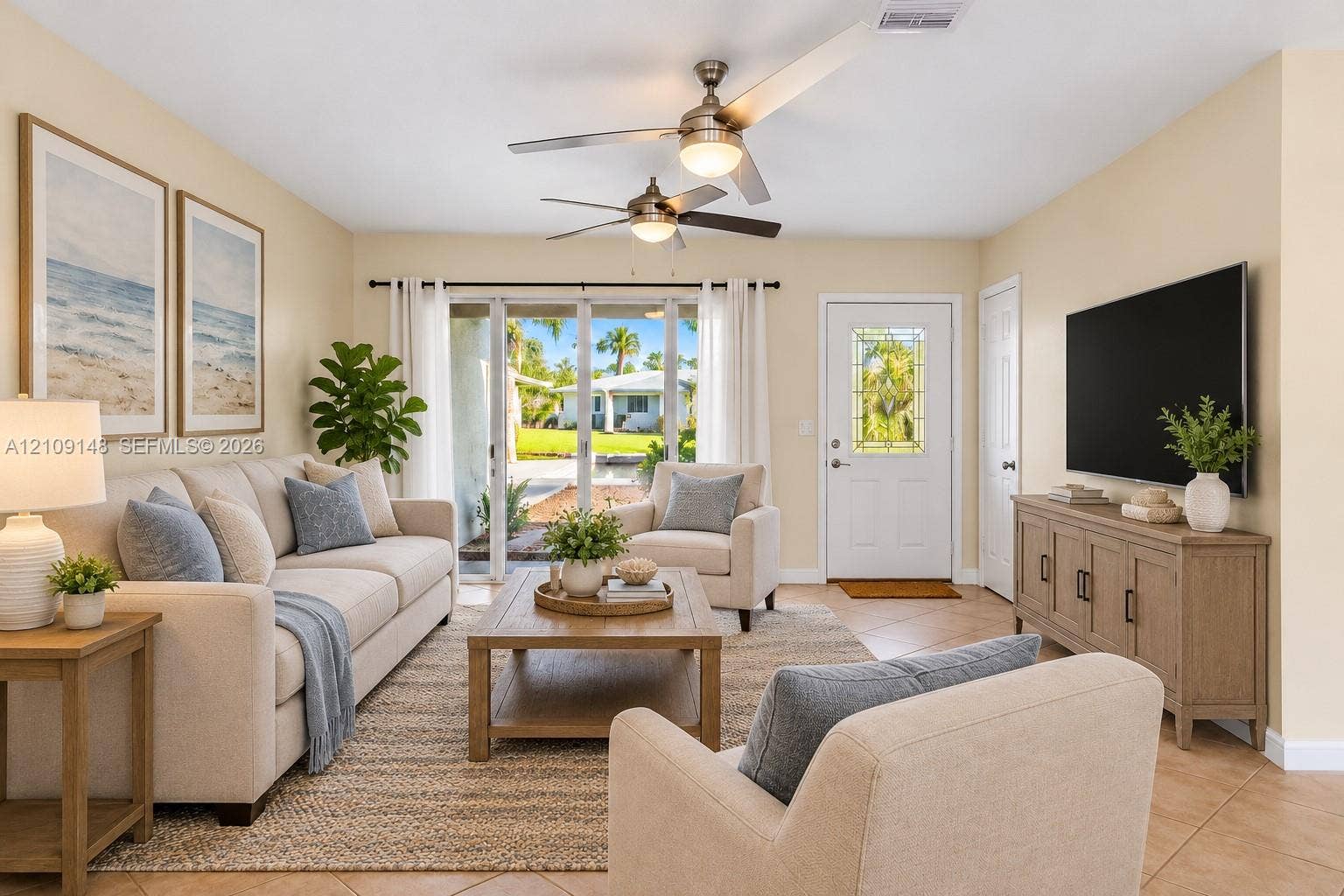 1701 SW 23rd Avenue, Fort Lauderdale, FL 33312 Living space featuring tile flooring, dual ceiling fans with integrated lighting, and multi-panel sliding glass doors providing outdoor access