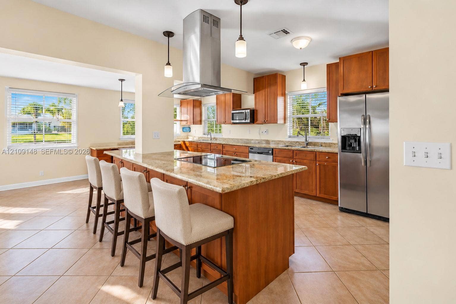 1701 SW 23rd Avenue, Fort Lauderdale, FL 33312 Kitchen featuring a center island with an integrated cooktop, stone-surface countertops, stainless steel appliances, custom wood cabinetry, and pendant lighting