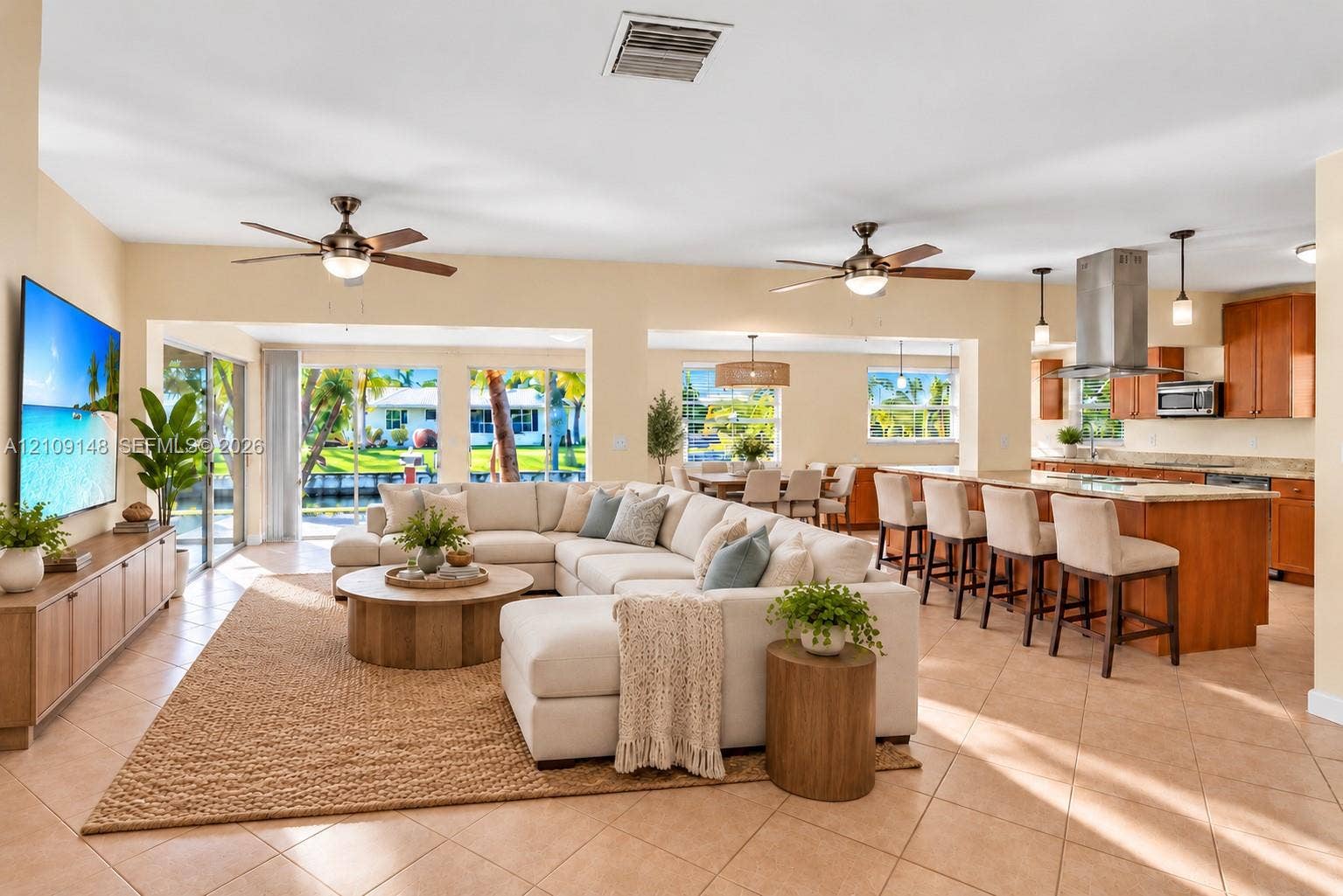 1701 SW 23rd Avenue, Fort Lauderdale, FL 33312 Open-concept living space featuring ceramic tile flooring, kitchen island with breakfast bar, stainless steel range hood, built-in cabinetry, and sliding glass doors