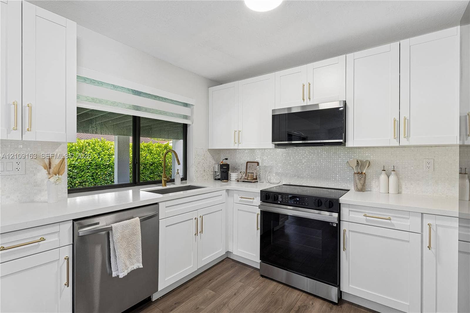 9122 SW 127th Avenue, Miami, FL 33186 Kitchen featuring white shaker-style cabinetry, quartz countertops, a mosaic tile backsplash, wood-finish flooring, and stainless steel appliances