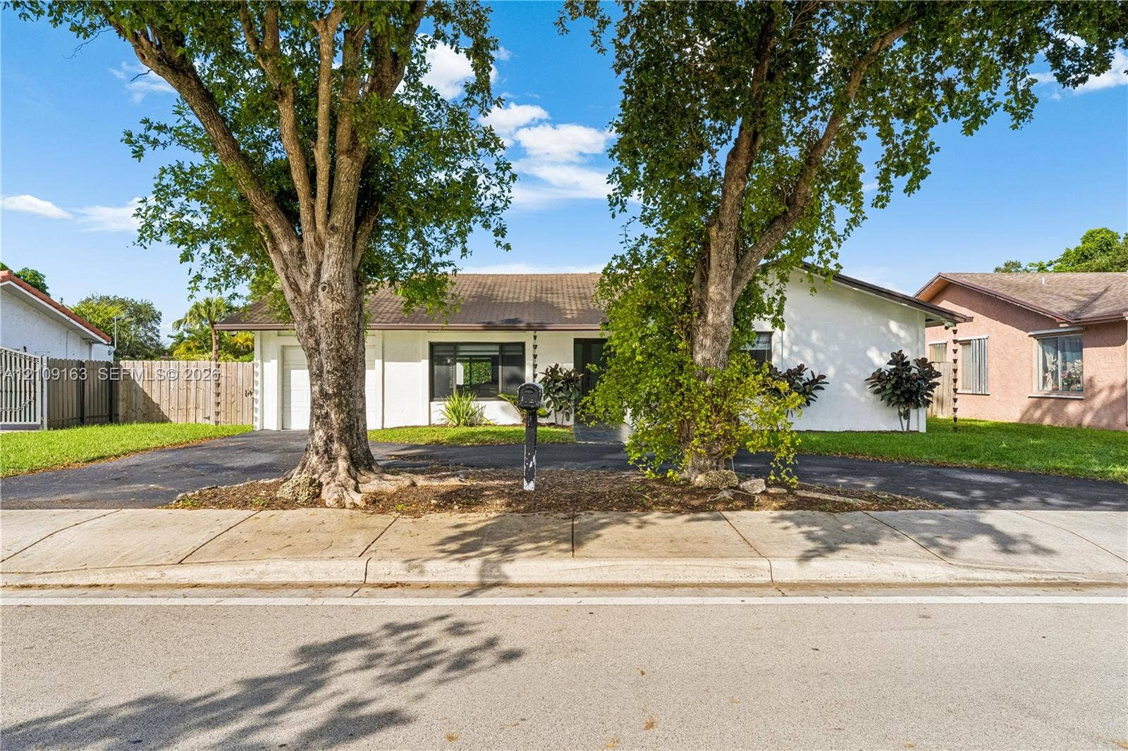 9122 SW 127th Avenue, Miami, FL 33186 Single-story exterior featuring white stucco siding, a concrete tile roof, a paved driveway, and mature landscaping