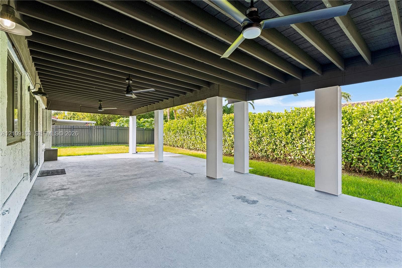 9122 SW 127th Avenue, Miami, FL 33186 Covered outdoor patio featuring a concrete floor, exposed beam ceiling, built-in ceiling fans, and structural support columns