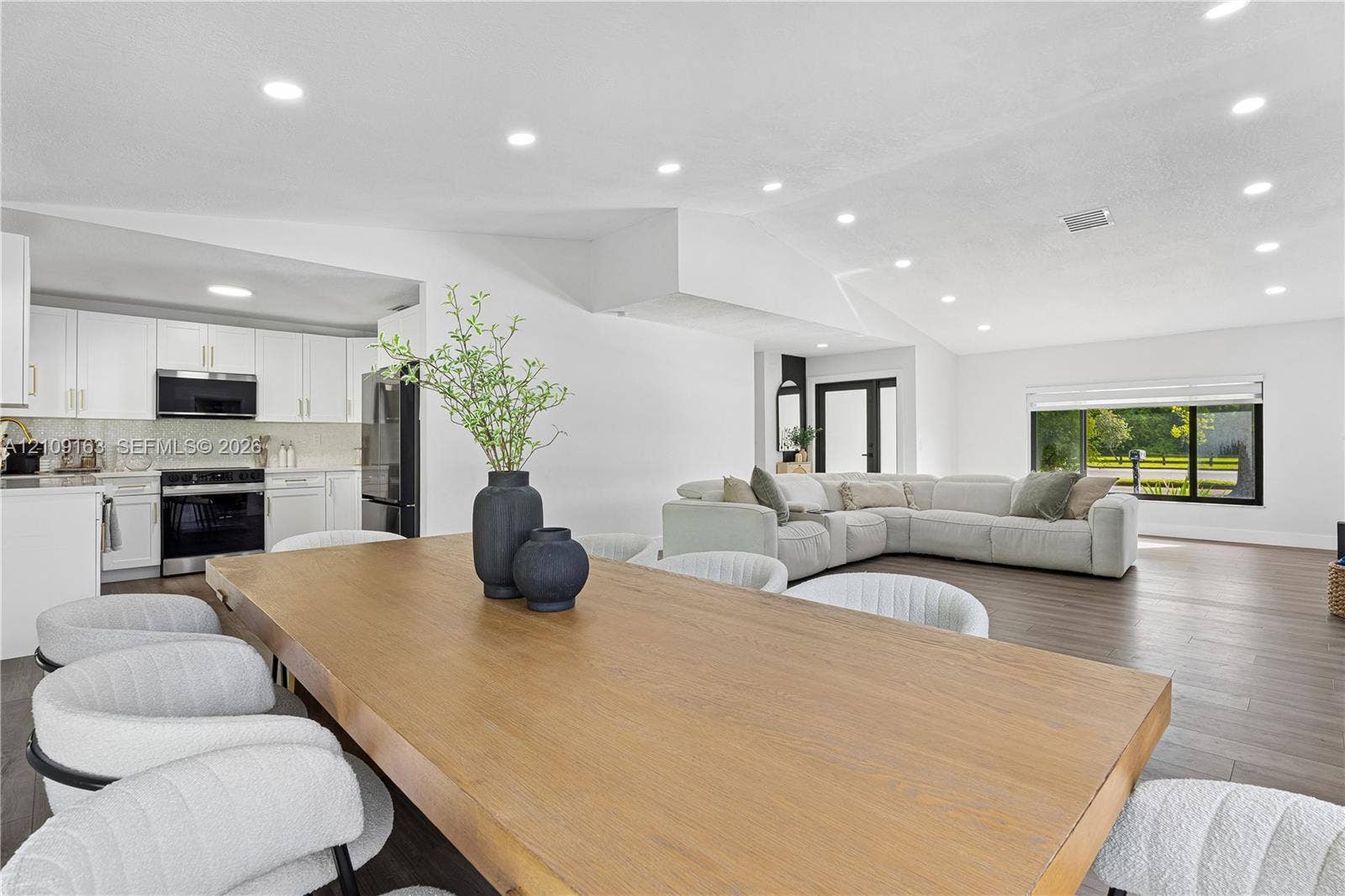 9122 SW 127th Avenue, Miami, FL 33186 Open-concept interior featuring vaulted ceilings, recessed lighting, wood-finish flooring, and crisp white cabinetry