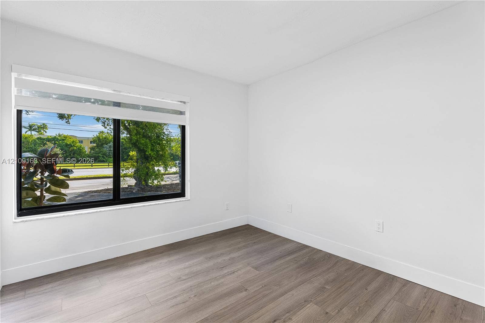 9122 SW 127th Avenue, Miami, FL 33186 Neutral wall finishes, wood-finish flooring, and a large black-framed window with integrated blind