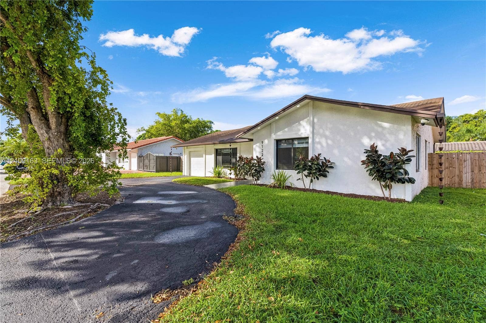 9122 SW 127th Avenue, Miami, FL 33186 Single-story residence featuring a white stucco exterior, asphalt driveway, manicured lawn, and wood-panel fencing