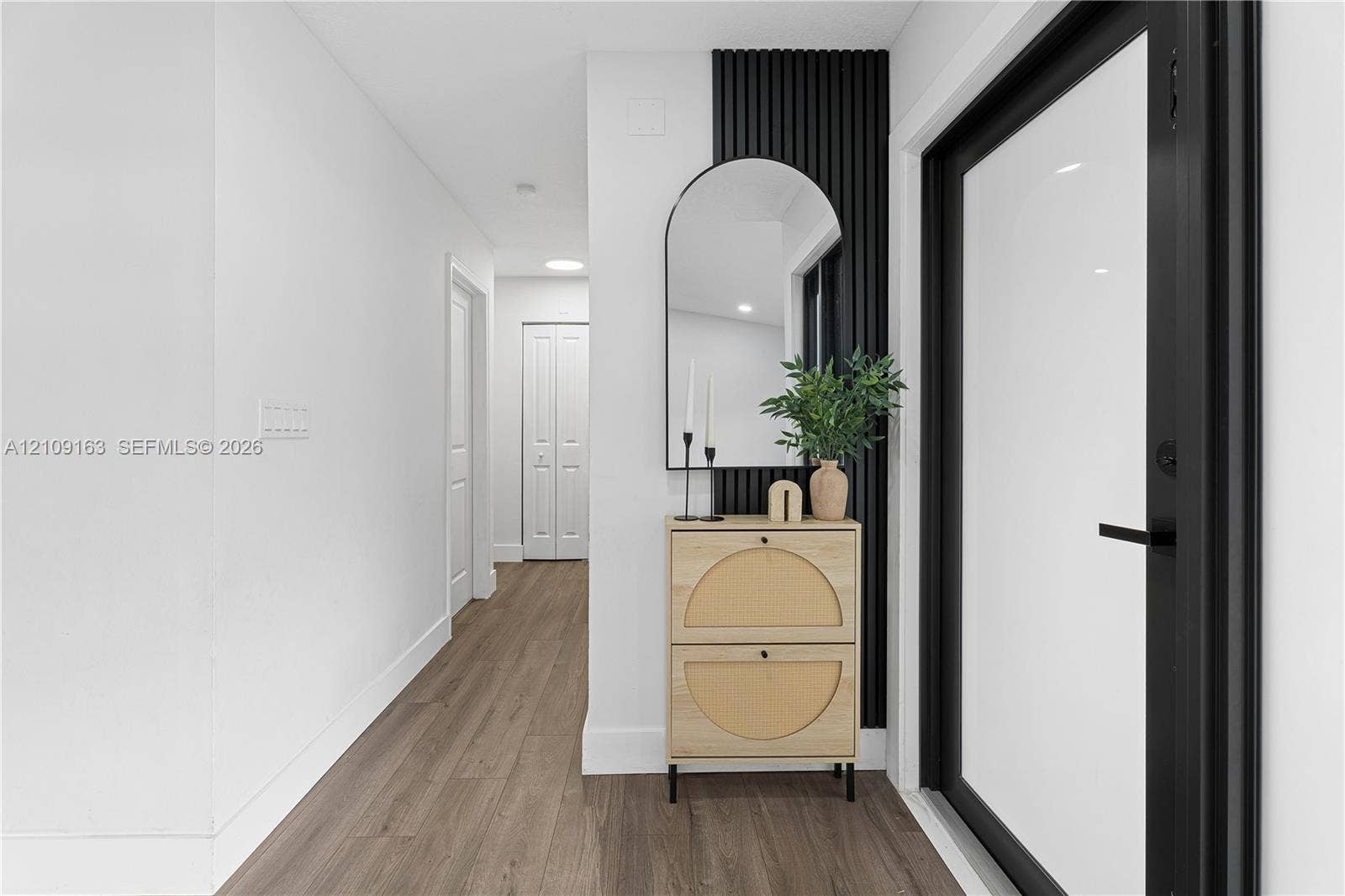 9122 SW 127th Avenue, Miami, FL 33186 Entryway featuring wood-finish flooring, a matte black door frame, and a vertical slat accent wall