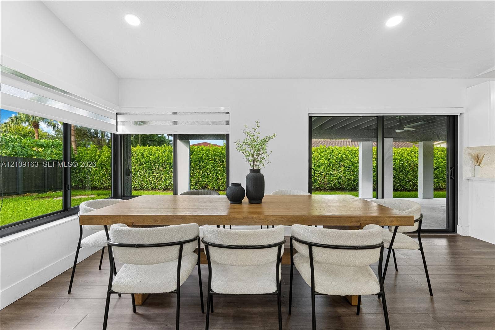 9122 SW 127th Avenue, Miami, FL 33186 Open-concept interior featuring wood-finish flooring, recessed lighting, and extensive floor-to-ceiling glass paneling with integrated sliding doors