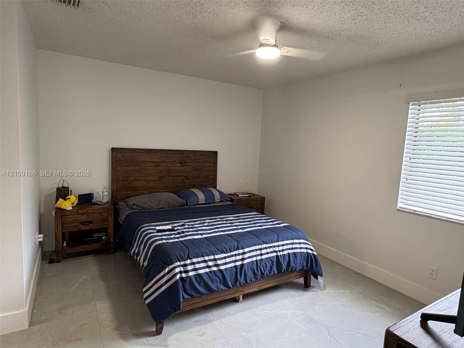 Neutral-toned tile flooring, white wall finish, white horizontal window blinds, and a white ceiling fan with an integrated light fixture
