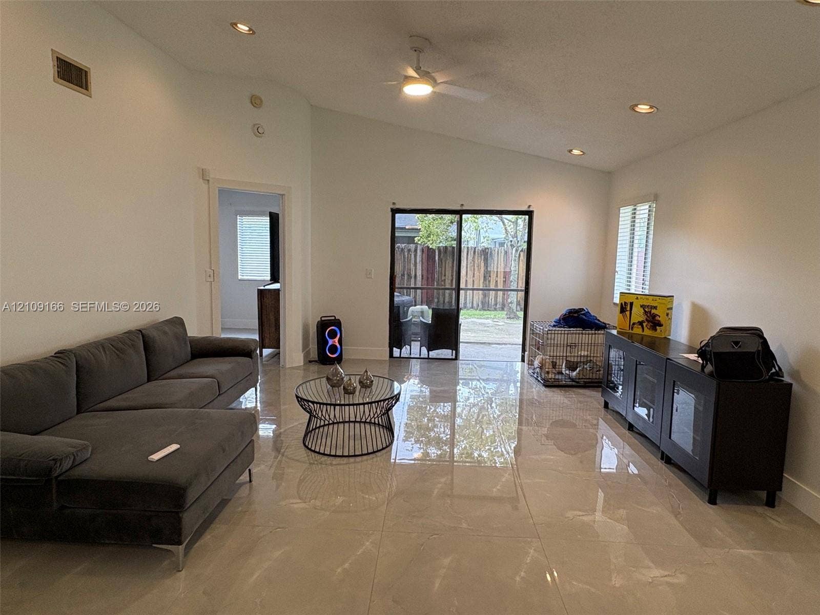 Large-format tile flooring, vaulted ceilings, recessed lighting, ceiling fan, and sliding glass doors