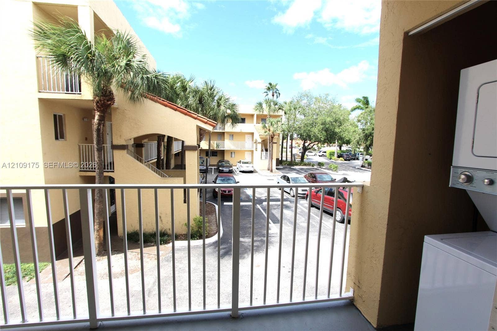 Covered balcony featuring white vertical railings and a built-in stacked laundry unit