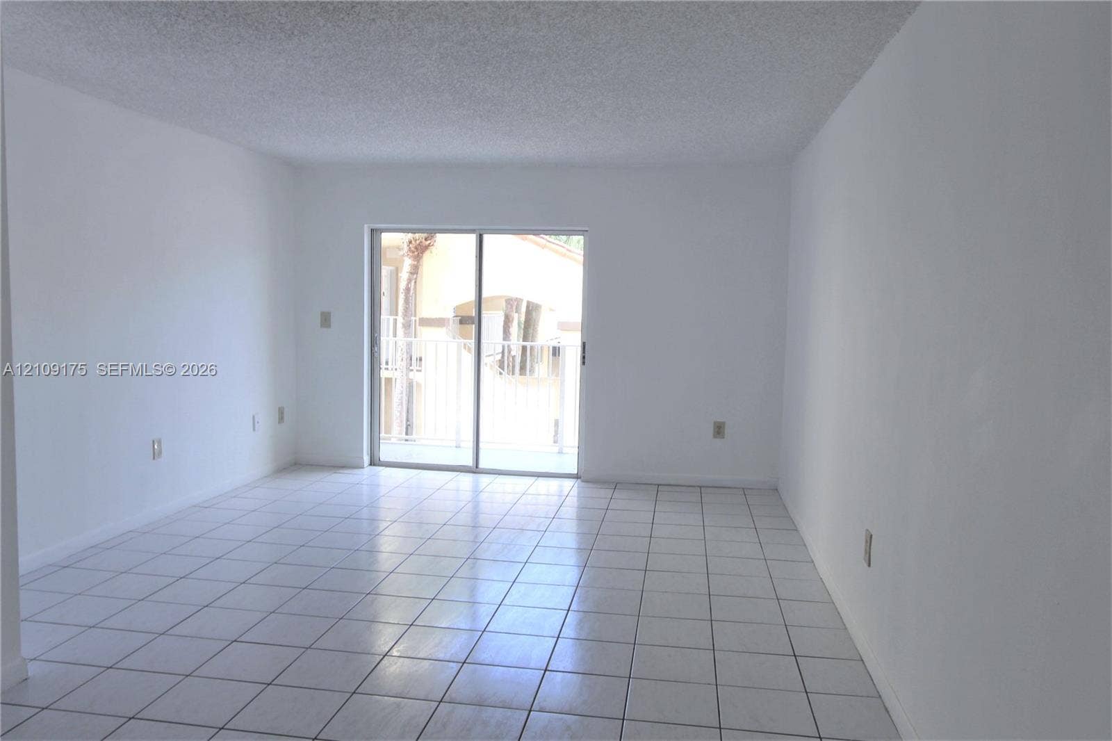 Interior space featuring white walls, large-format tile flooring, and a sliding glass door providing external access