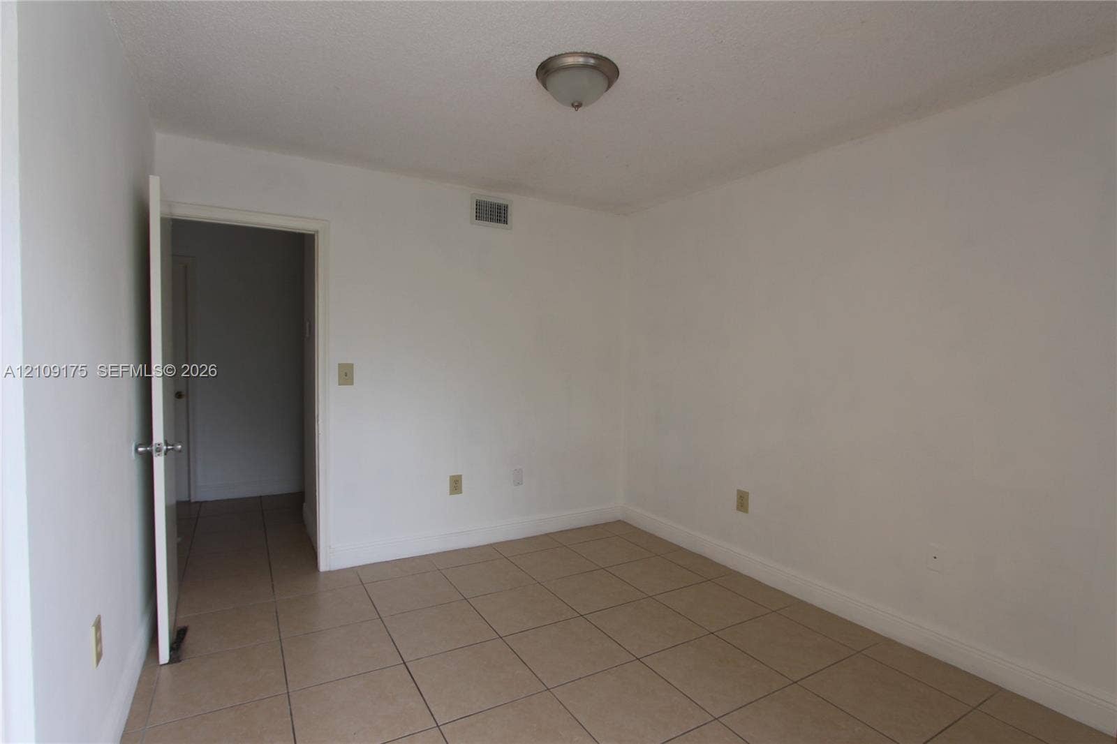 Neutral interior room featuring large-format ceramic tile flooring, a dome-style ceiling light fixture, and an interior swinging door