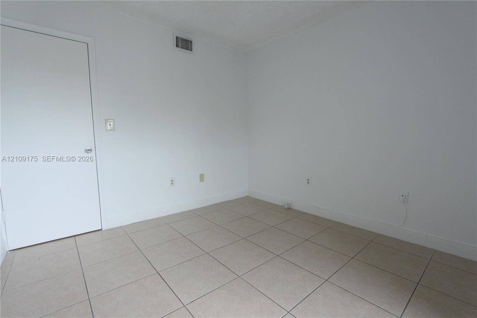 Room featuring neutral wall finishes, large-format tile flooring, and a solid-core interior door