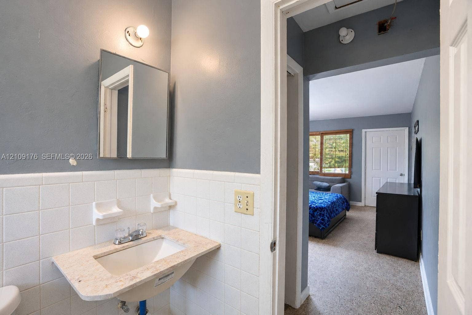 Wall-mounted vanity with a stone-finish countertop, integrated sink, and white ceramic tile backsplash featuring built-in soap dishes