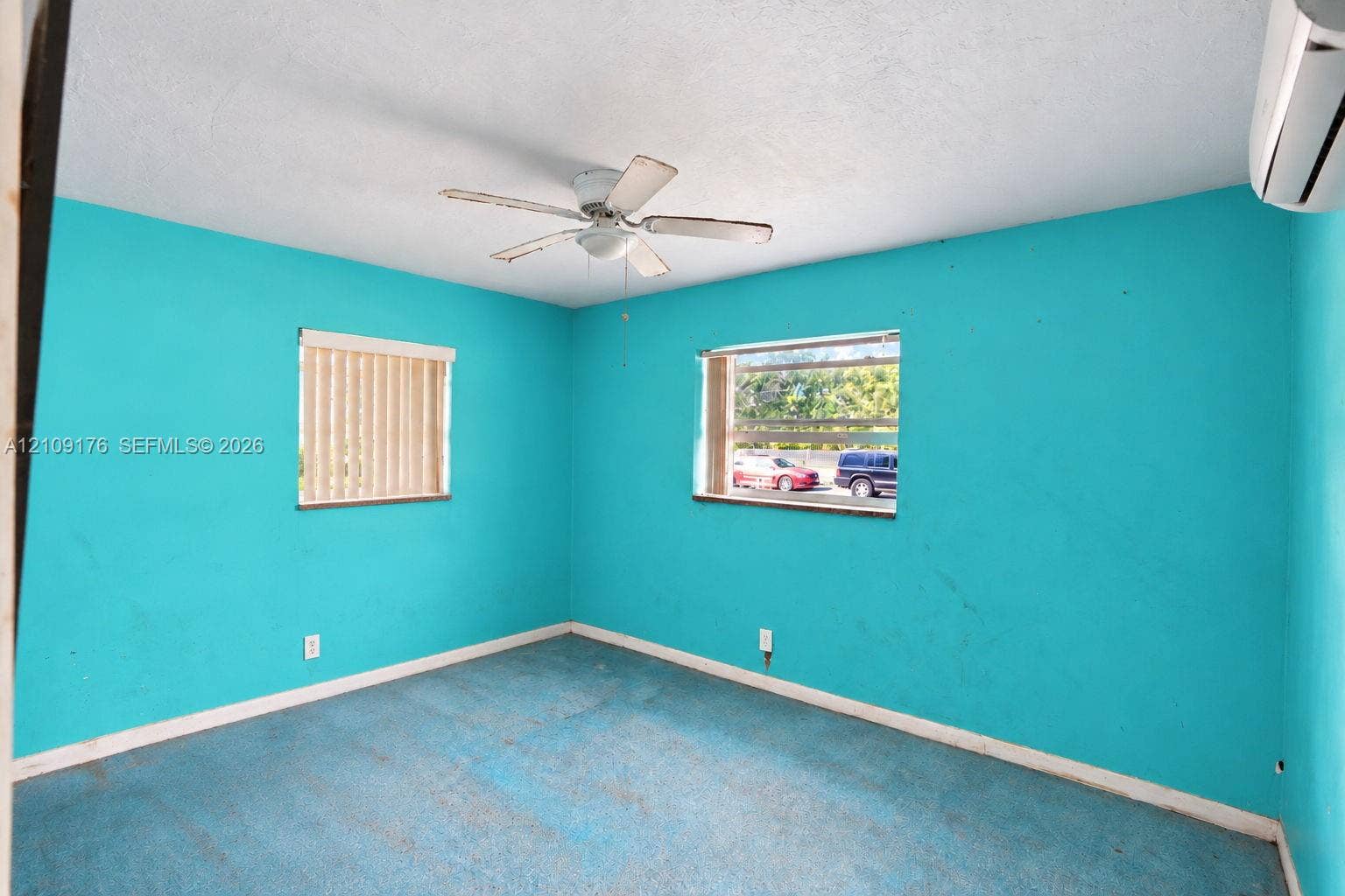 Interior room featuring two windows, a ceiling fan with light fixture, and a wall-mounted ductless air conditioning unit