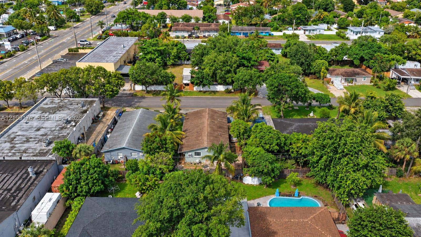 Aerial perspective featuring a detached residential structure, mature landscaping, and an inground swimming pool situated within a fenced perimeter