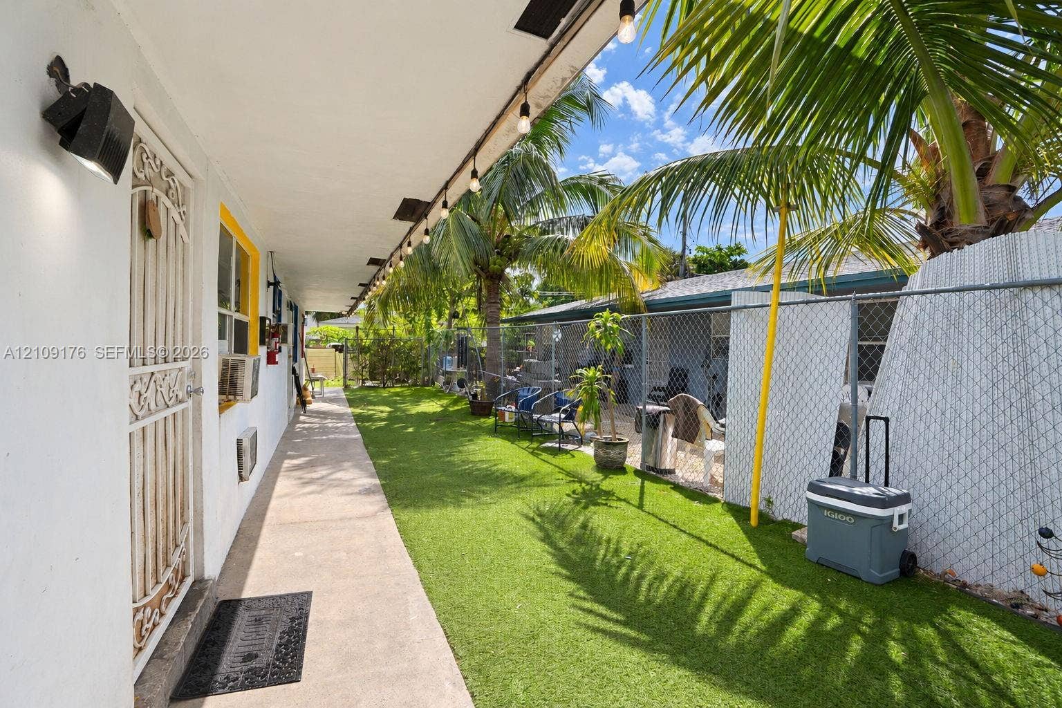 Covered concrete walkway featuring string lighting and metal security door