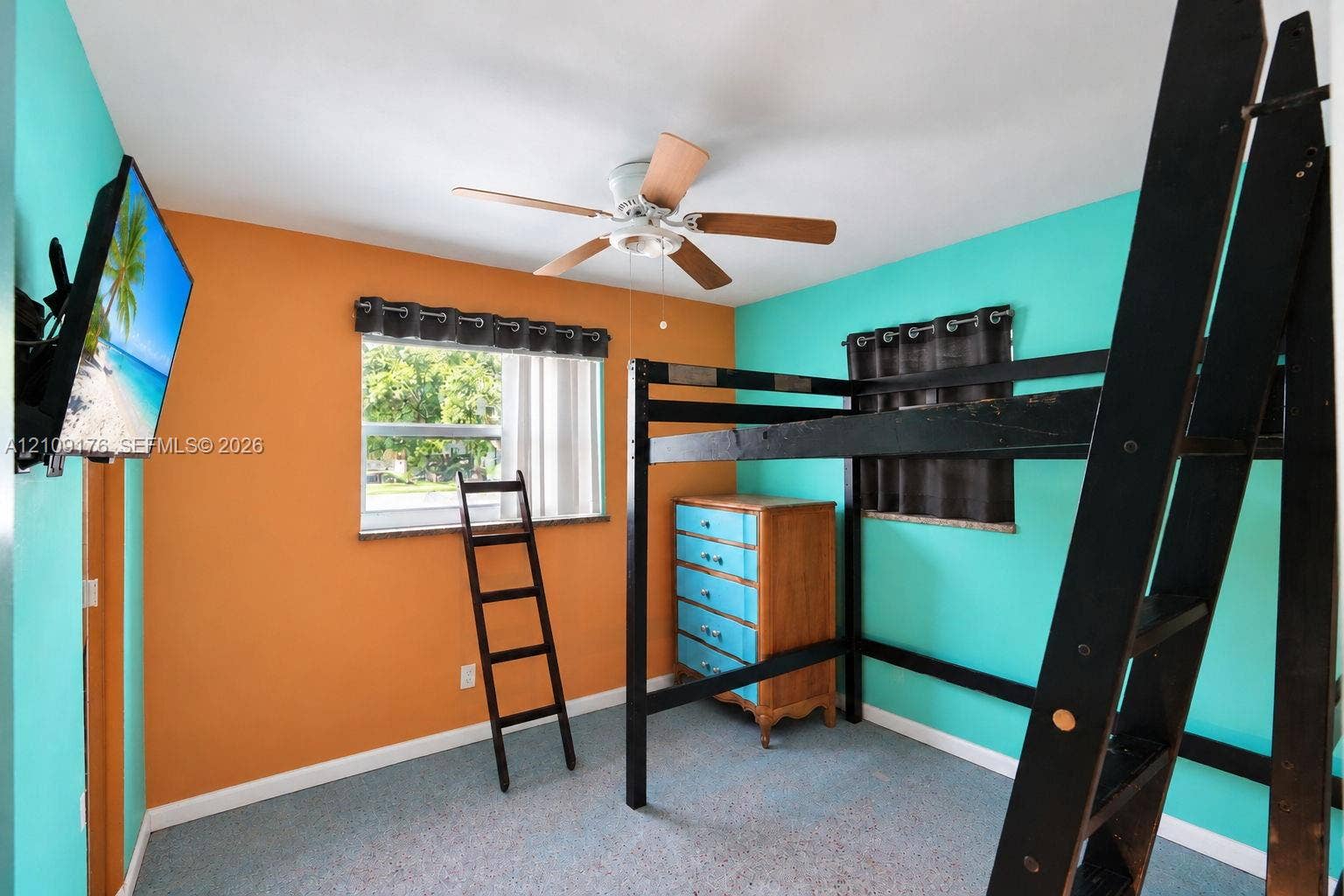 Room featuring a central ceiling fan with multi-blade design, large window with neutral-tone window treatments, and wall-to-wall carpeting